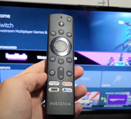 holding an Insignia TV Remote