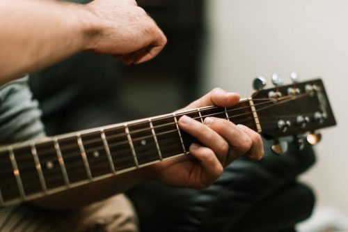 person's hand on guitar fret
