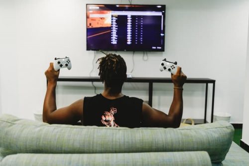 Man holding controllers in front of a TV