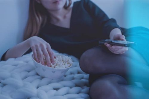 woman holding remote control and popcorn