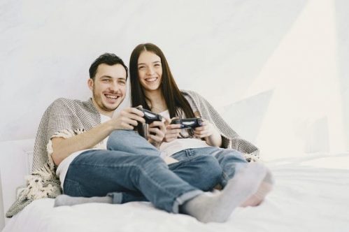 couple holding gaming consoles while smiling