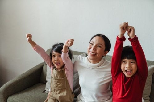 family of three getting excited while watching TV