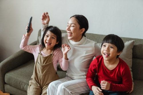 mother and children looking excited while sitting on sofa