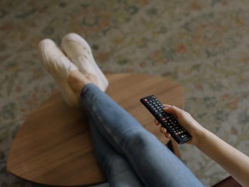 person holding LG remote while legs are crossed